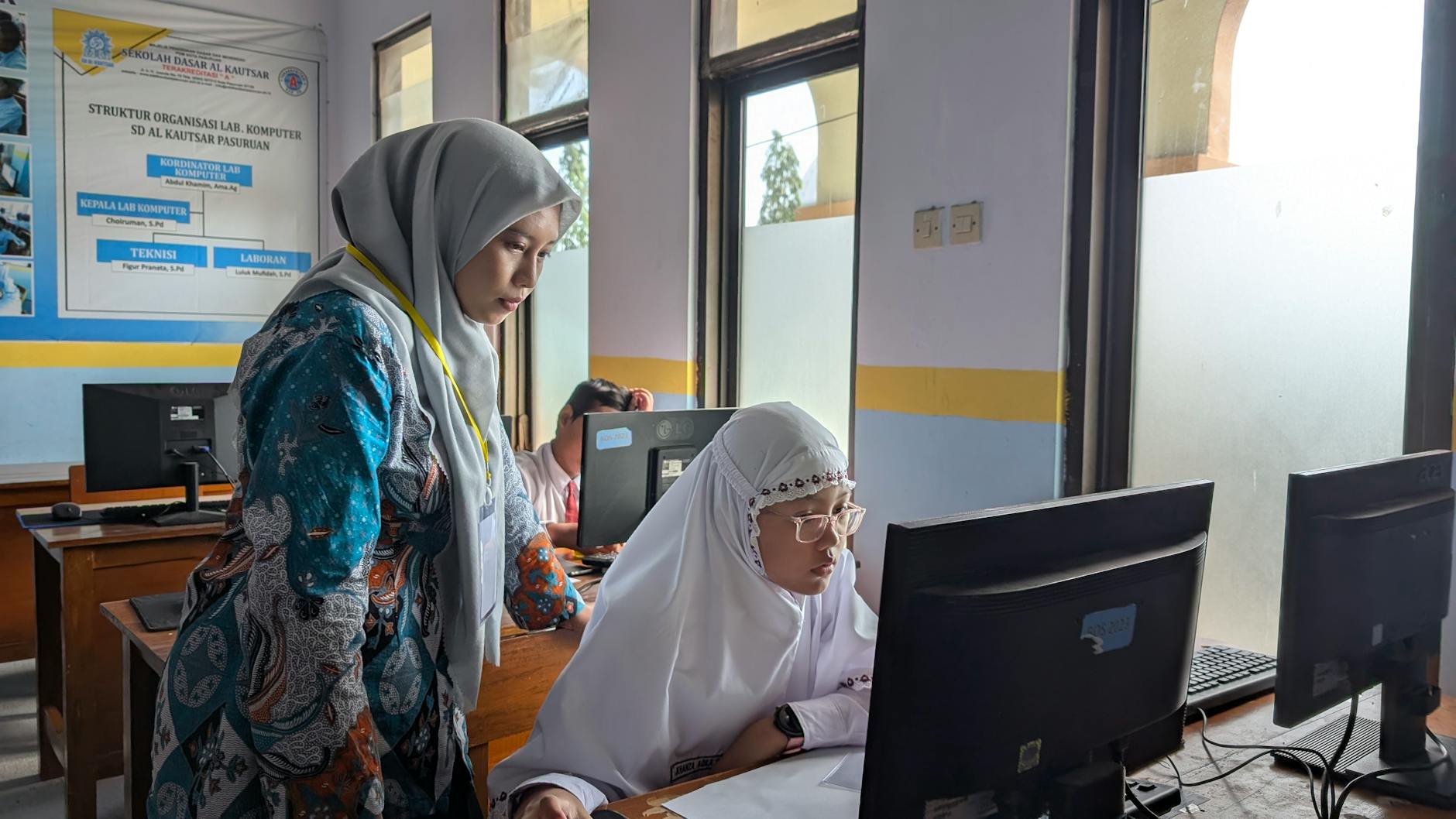 teacher assisting student in computer lab classroom