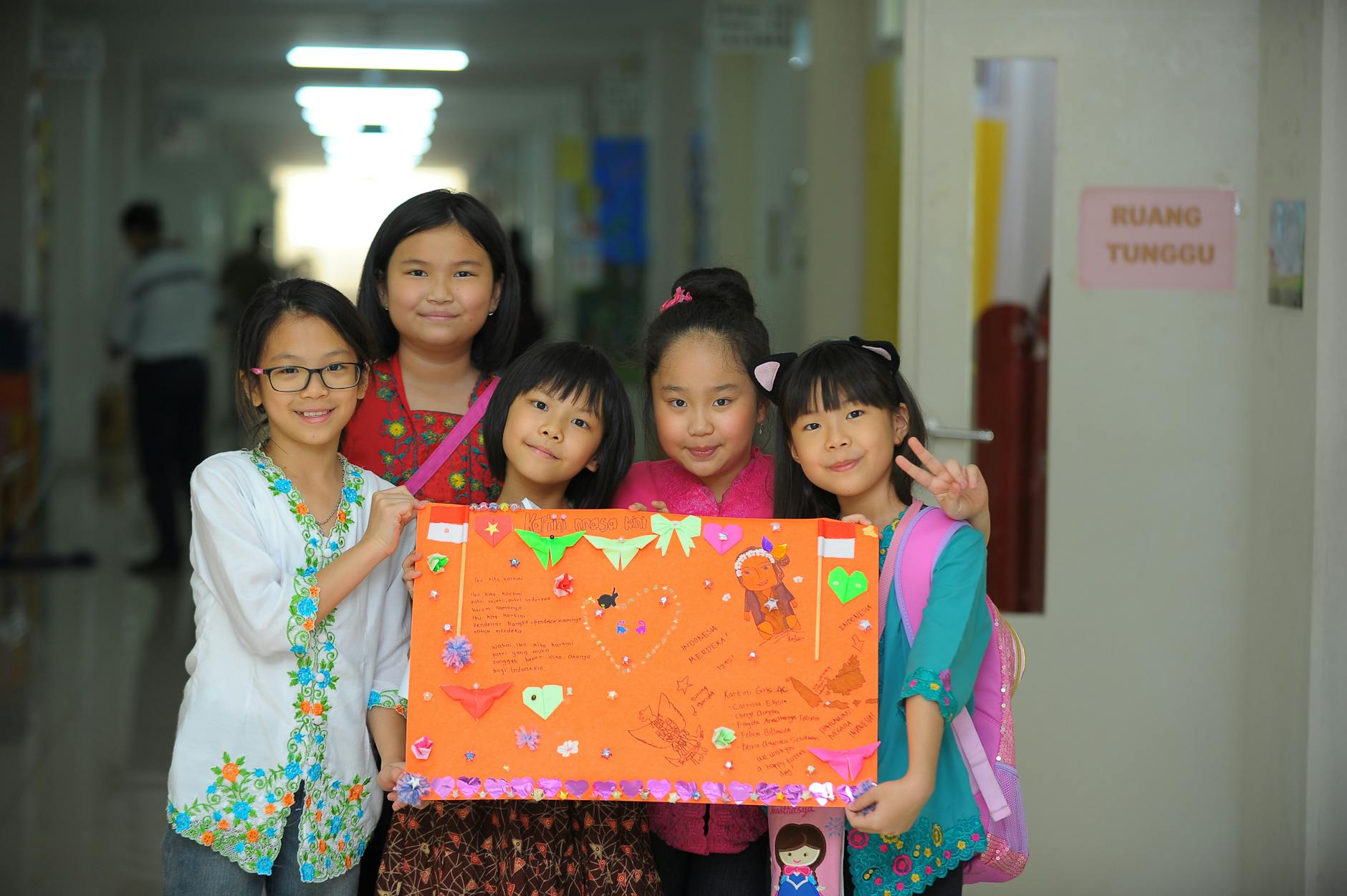 woman and girls posing with a paper collage in a school